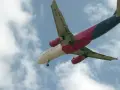 Samolot Wizzair w locie, widok od dołu, na tle błękitnego nieba z chmurami.