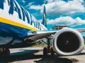 Fragment samolotu Ryanair z widocznym silnikiem i podwoziem na tle nieba.