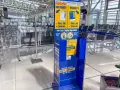 Niebieski stojak Ryanair z informacjami o bagażu w poczekalni lotniskowej.