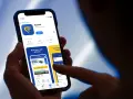 Dłoń trzyma smartfon z otwartą aplikacją Ryanair, widoczny ekran z logo i opcjami.