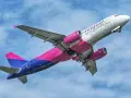 Samolot Wizz Air z różowymi silnikami i ogonem wznosi się na tle błękitnego nieba.
