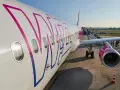 Samolot Wizz Air z pasażerami wsiadającymi po schodkach na lotnisku.