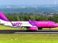 Różowy samolot Wizz Air na pasie startowym.