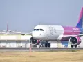 Samolot Wizzair z różowym ogonem na płycie lotniska.