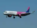Samolot Wizz Air z wysuniętym podwoziem na tle błękitnego nieba.
