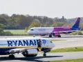 Samolot Ryanair na pierwszym planie, w tle samolot Wizz Air na pasie startowym.