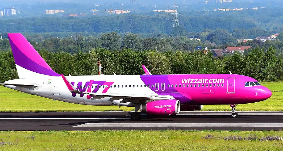 Różowy samolot Wizz Air na pasie startowym.