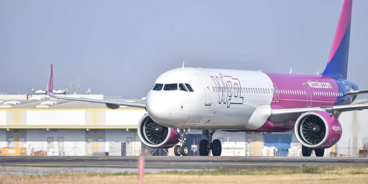 Samolot Wizzair z różowym ogonem na płycie lotniska.