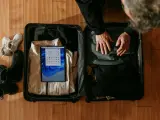 Osoba pakuje walizkę, w której widać ubrania, buty i tablet z ekranem Windows.