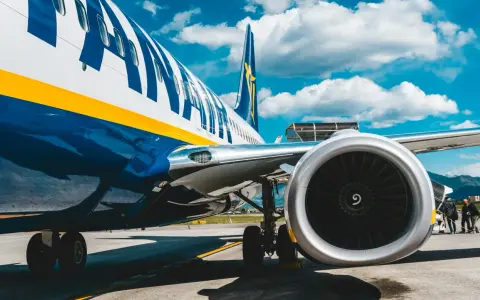 Fragment samolotu Ryanair z widocznym silnikiem i podwoziem na tle nieba.