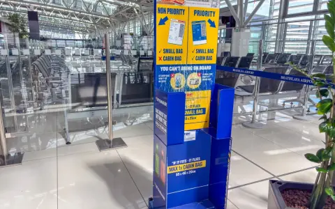 Niebieski stojak Ryanair z informacjami o bagażu w poczekalni lotniskowej.