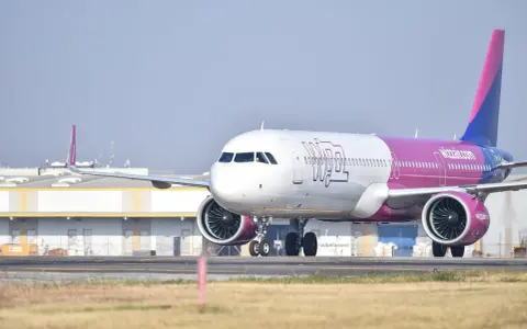 Samolot Wizzair z różowym ogonem na płycie lotniska.