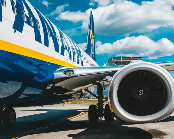 Fragment samolotu Ryanair z widocznym silnikiem i podwoziem na tle nieba.