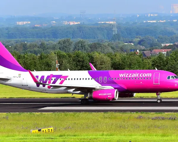 Różowy samolot Wizz Air na pasie startowym.