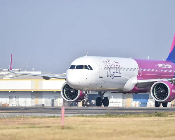 Samolot Wizzair z różowym ogonem na płycie lotniska.