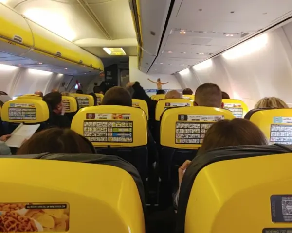 Widok z wnętrza samolotu Ryanair z żółtymi siedzeniami i pasażerami.