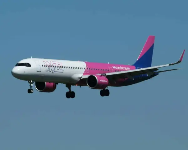 Samolot Wizz Air z wysuniętym podwoziem na tle błękitnego nieba.