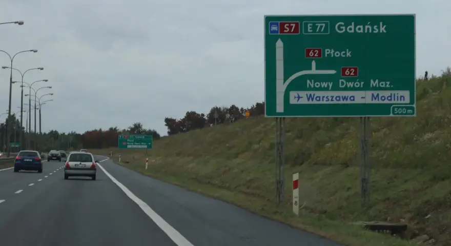 Zielony znak drogowy z kierunkami: Gdańsk, Płock, Nowy Dwór Maz., Warszawa-Modlin.