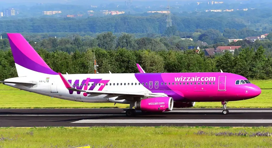 Różowy samolot Wizz Air na pasie startowym.