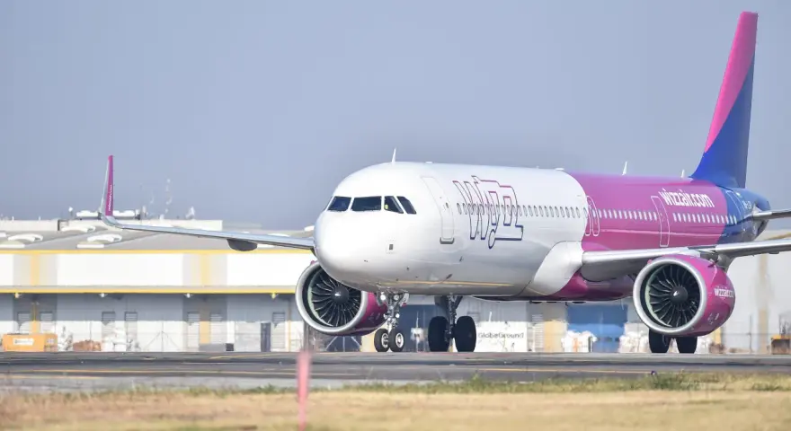 Samolot Wizzair z różowym ogonem na płycie lotniska.