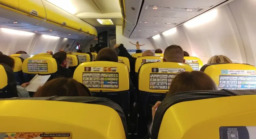 Widok z wnętrza samolotu Ryanair z żółtymi siedzeniami i pasażerami.