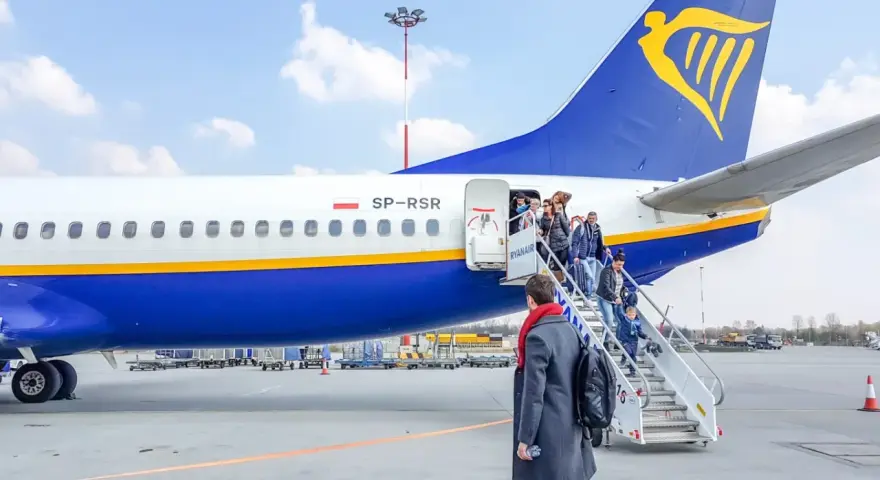 Pasażerowie wsiadają po schodkach do samolotu Ryanair.