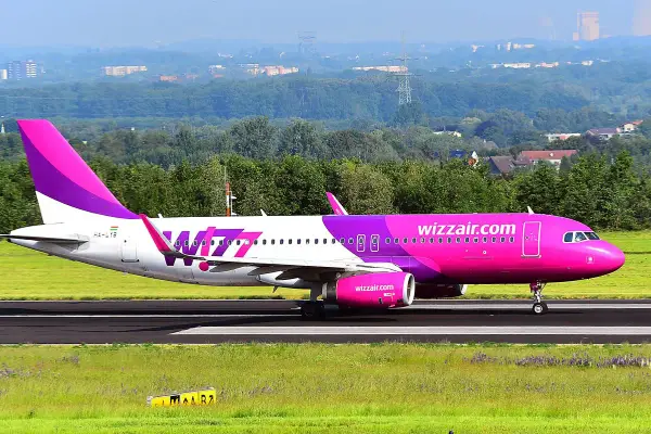 Różowy samolot Wizz Air na pasie startowym.